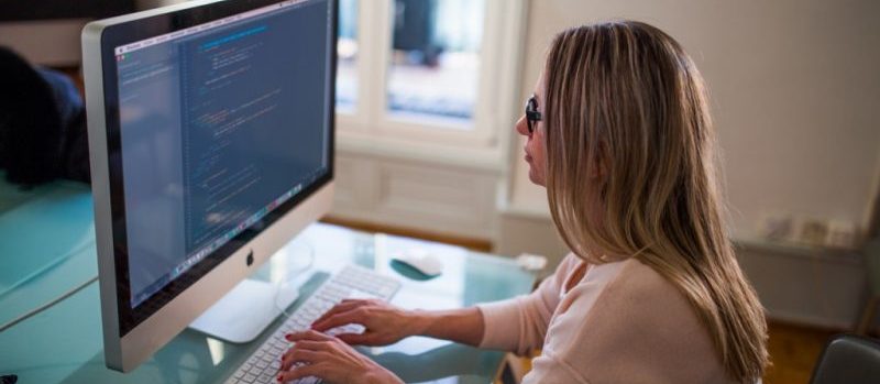 a woman is operating a computer (mac)